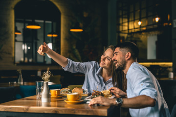 couple taking picture while eating in restaurant