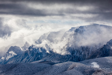 Beautiful mountain panorama in winter with fog and clouds. Bucegi mountains seen from Postavaru, Romania.