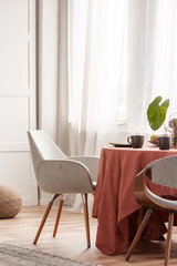 Living and dining room interior with grey couch and table covered with orange tablecloth