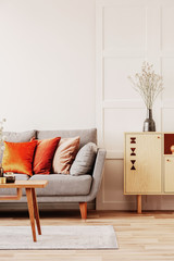 Copy space on empty white wall of fashionable living room interior with grey and orange design