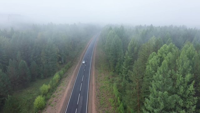 Flying over highway in siberian taiga forest in misty morning. Natural scenery in Buryatia, Russia