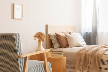 Bright and natural hotel room interior with single bed and wooden nightstand with flowers