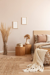 Beige kid's room with wooden nightstand with flowers and single bed and wicker basket with white blanket