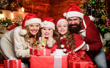 Fototapeta na wymiar New 2020 Year is coming. Happy family celebrate new year. merry christmas. Father and mother love kids. small children and parents in santa hat. lot of xmas present boxes. Portrait loving family