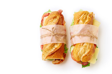 Two fresh big baguette sandwiches with bacon, chedder cheese, mustard, lettuce and vegetables isolated on white background