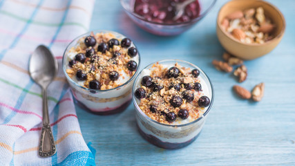 Traditional homemade French dessert of berries, grated nuts, jam and yogurt - parfait in cups on a blue wooden background, top view