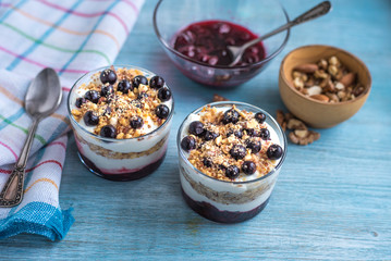 Traditional homemade French dessert of berries, grated nuts, jam and yogurt - parfait in cups on a blue wooden background, top view