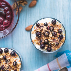 Traditional homemade French dessert of berries, grated nuts, jam and yogurt - parfait in cups on a blue wooden background, top view