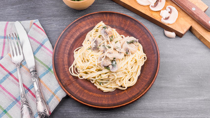 Traditional Italian pasta - spaghetti with cream sauce of champignon mushrooms and parsley on a plate, top view