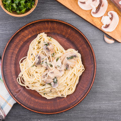 Traditional Italian pasta - spaghetti with cream sauce of champignon mushrooms and parsley on a plate, top view