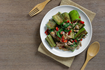 top view of stir fried eggplant with pork in a ceramic dish on wooden table. asian homemade style food concept.