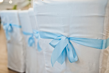 Beautiful wedding set decoration in the restaurant. Blue ribbons on chairs.
