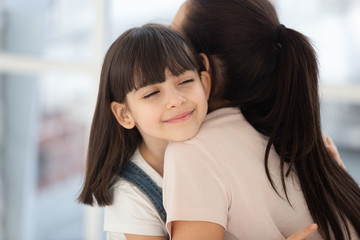 Little girl hugging mom showing love and care