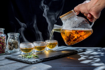 Tea time to brew loose-leaf or flower . dark mood.Hot water is poured from the kettle into a cup with tea leaves.