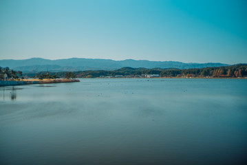 Calm surface of lake and long shot of layered mountains at Gangneung, South Korea