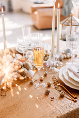 New Year 2019. New Year mood. Table with a gold tablecloth, decorated with candles and tableware for celebration. Festive still life by candlelight. Bengal lights in the foreground. Close-up.