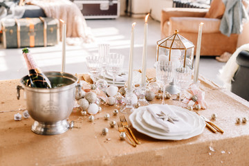 New Year 2019. New Year mood. Table with a gold tablecloth, decorated with candles and tableware for celebration. Festive still life by candlelight. Close-up.