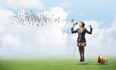 Woman with megaphone sitting on big light bulb