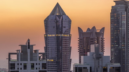 View of illuminated skyscrapers with lights from windows in Dubai at sunset aerial timelapse