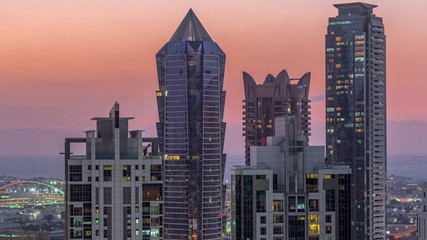 View of illuminated skyscrapers with lights from windows in Dubai at sunset aerial timelapse