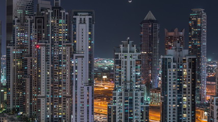 Fototapeta premium Modern residential and office complex with many towers aerial night timelapse at Business Bay, Dubai, UAE.
