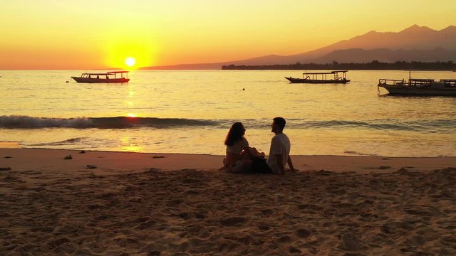 Tourist Couple Enjoying The Beautiful Orange Scenery Of The Sunset On The Peaceful Beach in  Patong,Thailand - Wide Pan Shot