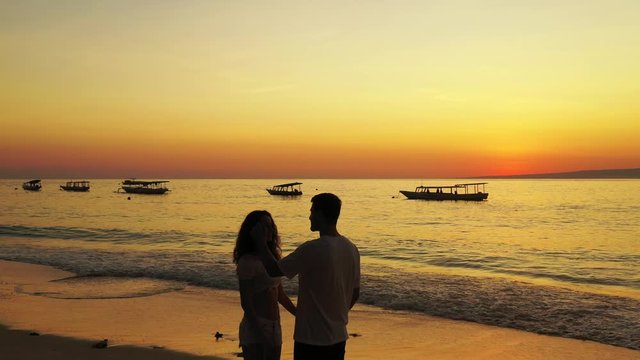 Ko Samui Island, Thailand - Romantic Couple Enjoying Their Vacation On The Beach With Beautiful Sunset and Boats Floating By The Sea - Wide Shot