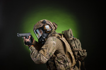 a male soldier in military clothes with a weapon on a dark background in a gas mask