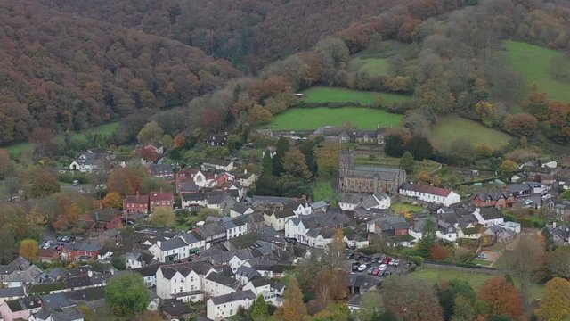 Aerial dolly pull back reveal of valley landscape from All Saints church in Dulverton, located on the River Barle on the edge of Exmoor, UK.