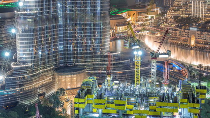 Aerial view of a skyscraper under construction with huge cranes night timelapse in Dubai.