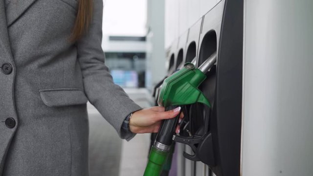 Woman fills petrol into her car at a gas station close-up. Slow motion