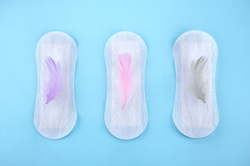 Menstrual pad with feathers on color background