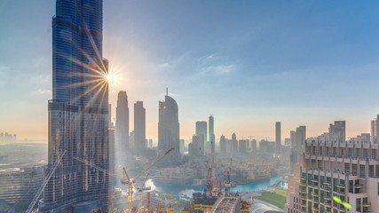 Panoramic skyline view of Dubai downtown during sunrise with mall, fountains and Burj Khalifa aerial morning timelapse