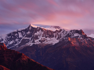 Sunrise overlooking the majestic Himalayan peaks - Annapurna IV and Annapurna II, covered with clouds illuminated by the sunrise.