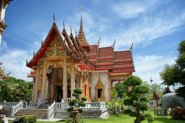 Fototapeta premium View of the traditional Asian pagoda. A white building with gold trim and a red roof against the sky. Buddhist temple facade in Thailand.