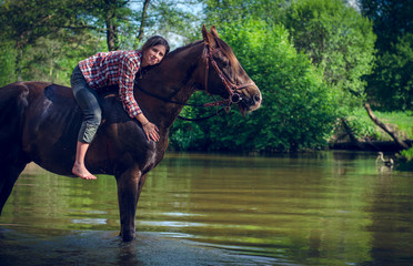 portrait of girl riding red trakehner stallion horse in the river in the summer