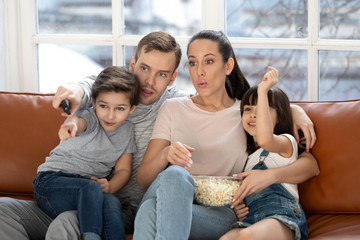 Young parents enjoy movie time at home with little kids