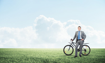 Fototapeta premium Smiling businessman with bicycle outdoors