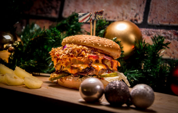 Christmas burger with pineapples. Burger on a background of a brick wall and Christmas tree. Christmas toys in the foreground.