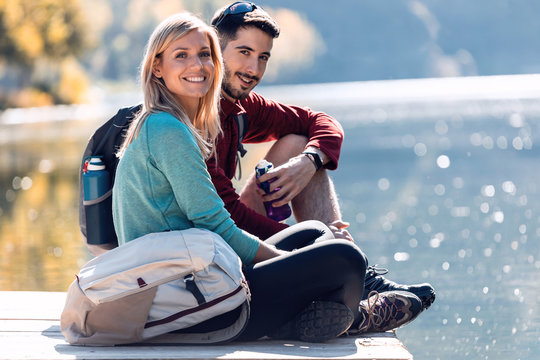 Two travel hikers looking at camera while enjoying the nature in the lake of the mountain.