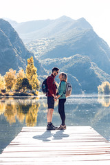 Two travel hikers in love kissing in front of the lake in mountain.