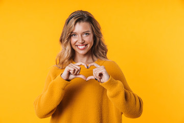 Image of blonde woman in warm sweater laughing and showing heart shape