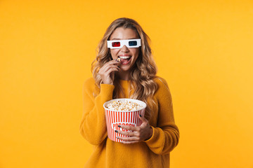 Image of woman in 3D glasses eating popcorn while watching movie - obrazy, fototapety, plakaty