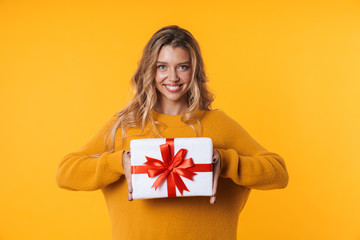 Fototapeta premium Image of beautiful blonde woman in warm sweater smiling and holding present box