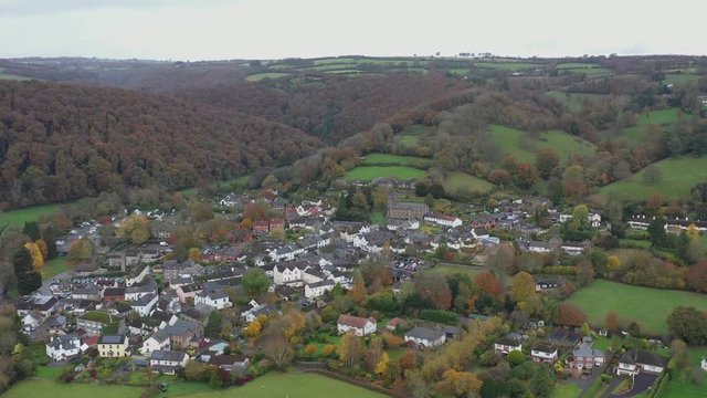 Wide dolly aerial reveal of landscape and valley surrounding the market town of Dulverton, located on the River Barle on the edge of Exmoor, UK.