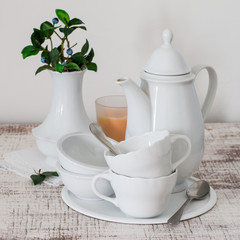 White porcelain tableware for coffee and a vase with a branch  blueberry on an old wooden table. Selective focus.