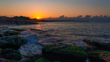 Splashing waves on the coastal cliffs at sunset