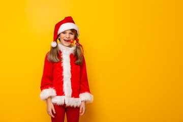Fototapeta na wymiar Little girl in Santa costume blowing party whistle