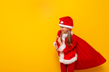 Fototapeta na wymiar Child wearing Santa costume carrying huge sack of Christmas presents