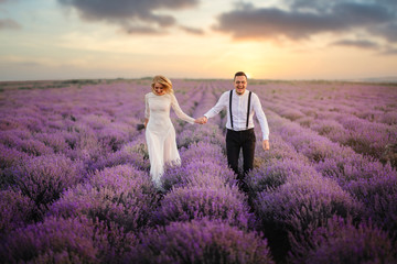 Happy newlyweds running along blooming lavender field